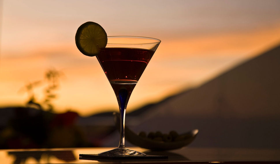Detail of a cocktail with fruit, silhouetted against a beautiful sunset.