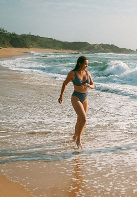 Girl running on beach in two piece bikini on hot summer day