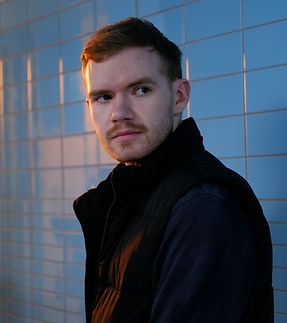 Man Standing against a blue tiled wall, golden sunlight