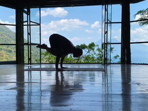 A man performs a complex yoga pose in front of a beautiful landscape