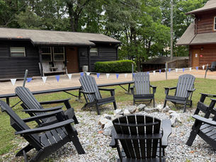 A fire pit and chairs sit in front of a cozy summer camp cabin on Lake Allatoona