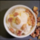 Cup of ice cream with nuts on top.