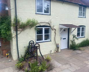 Painting in progress on cottage exterior by Adams Painting Services. Ladder and supplies r