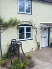 Painting in progress on cottage exterior by Adams Painting Services. Ladder and supplies r