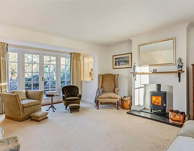 Cozy living room with fireplace, chairs, and window overlooking trees home.