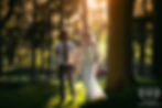 A bride and groom in wedding attire walking in a wood in Leeds Yorkshire at sunset and smiling at each other