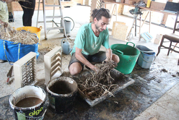 Théo Pargemin mélange la terre et la paille pour montrer la technique du torchis
