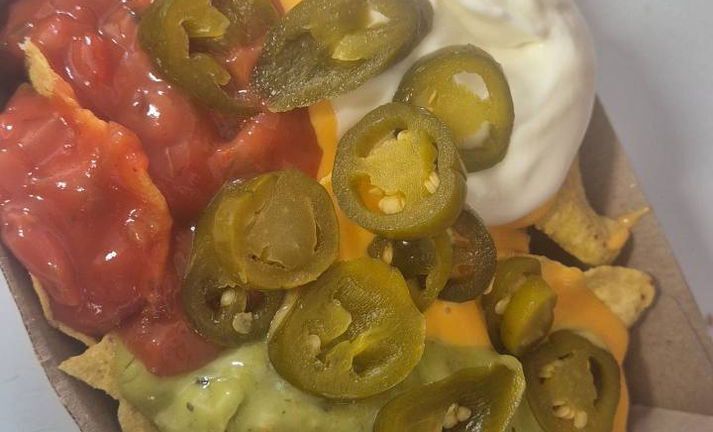 Delicious nachos with guacamole, salsa, cheese, jalapenos and sour cream