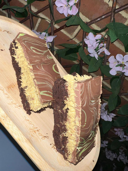 Chocolate cake slices on a wooden board, with flowers in background.