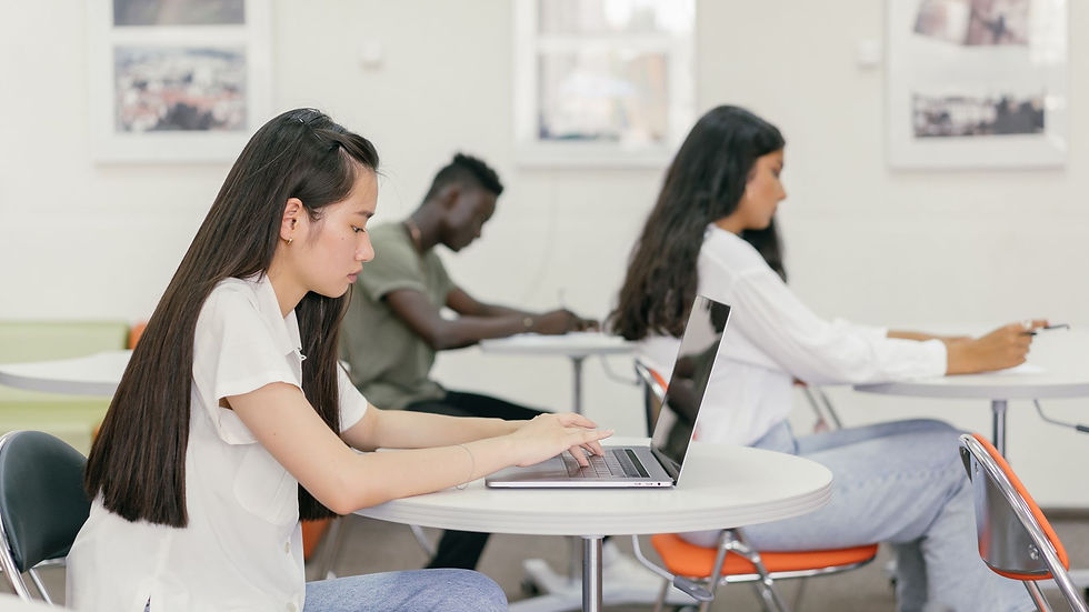 Students focused on learning in a contemporary university setting with laptops and notebooks.