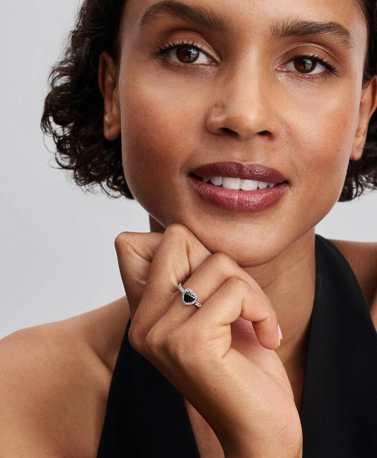Woman wearing Pandora Elevated Black Heart Ring, smiling with ring on finger.