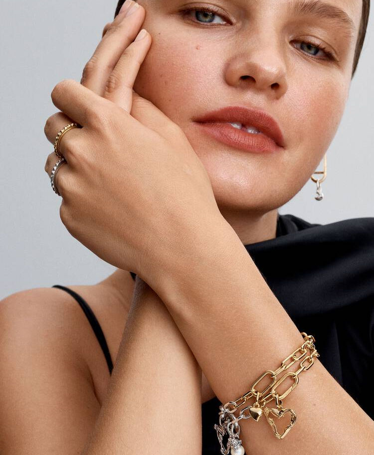 Woman with gold jewelry, including rings and bracelets, wearing black top.