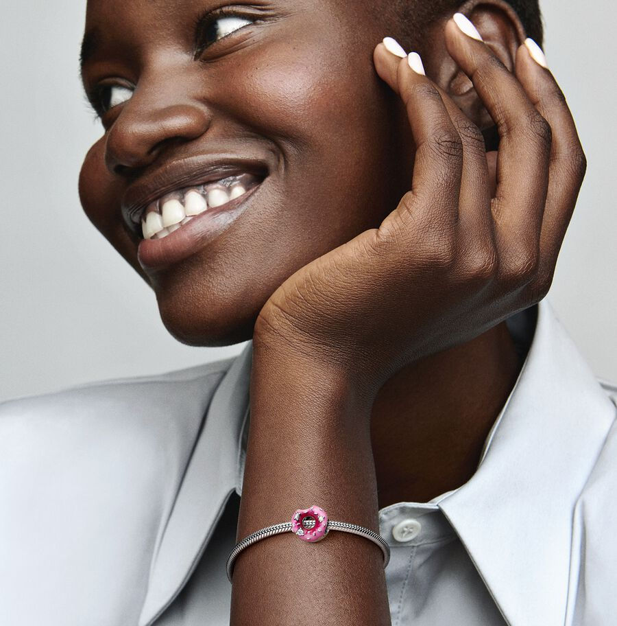 Smiling woman wearing silver bracelet with pink jewel, smiling, looking away Jewels by the Sea.