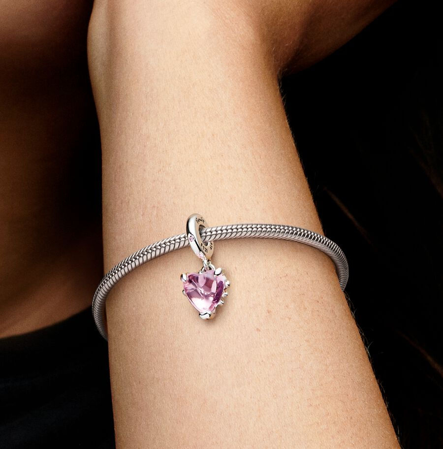 Woman's arm with a heart-shaped pink charm bracelet. Jewels by the Sea.