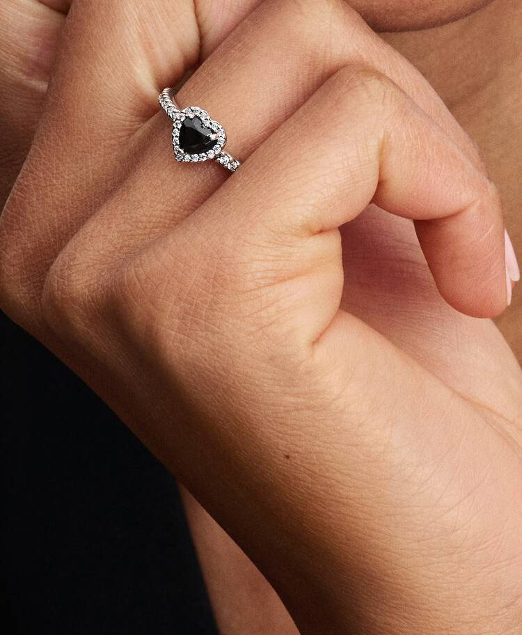 Hand with Pandora Elevated Black Heart Ring, close-up shot on black shirt.