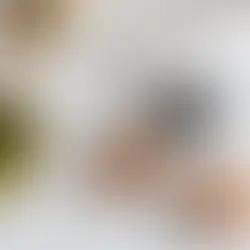 Overhead view of a light wooden table with green apples, baked muffins on white plates, a cup of coffee, and a newspaper.