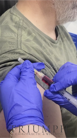 Gloved hand injecting man's arm with syringe. TRIUMPH CHIROPRACTIC & WELLNESS.