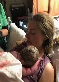 Mother resting in hospital bed holding her newborn baby boy skin to skin shortly after birth.