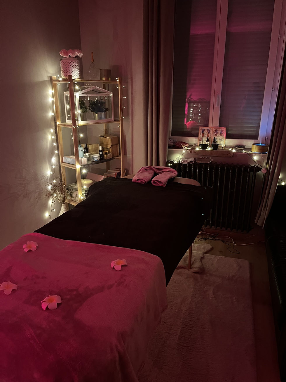 Ambiance chaleureuse et apaisante dans le cabinet avant un massage, éclairée par des lumières tamisées et décorée de fleurs délicates