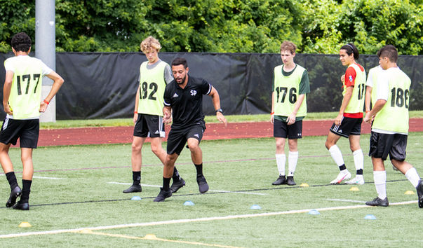 Coach demonstrates drill for young athletes on turf
