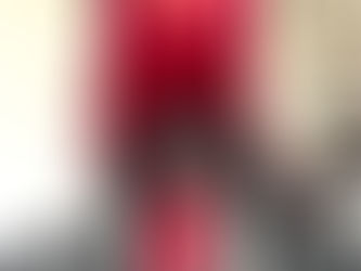 Dominant woman in velvet and PVC outfit seated in a controlled setting.