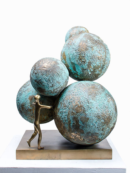 "Breaking New Grounds," a bronze sculpture by Beatriz Gerenstein, depicts spheres bathed in shades of blue and green. A solitary human figure stands opening a path through the spheres, symbolizing the innate human spirit to break through boundaries, explore uncharted territories, and venture fearlessly into the infinite