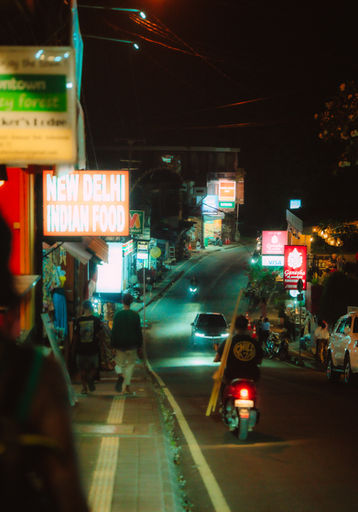 scooter en pleine rue d'Ubud de nuit et ses commerces