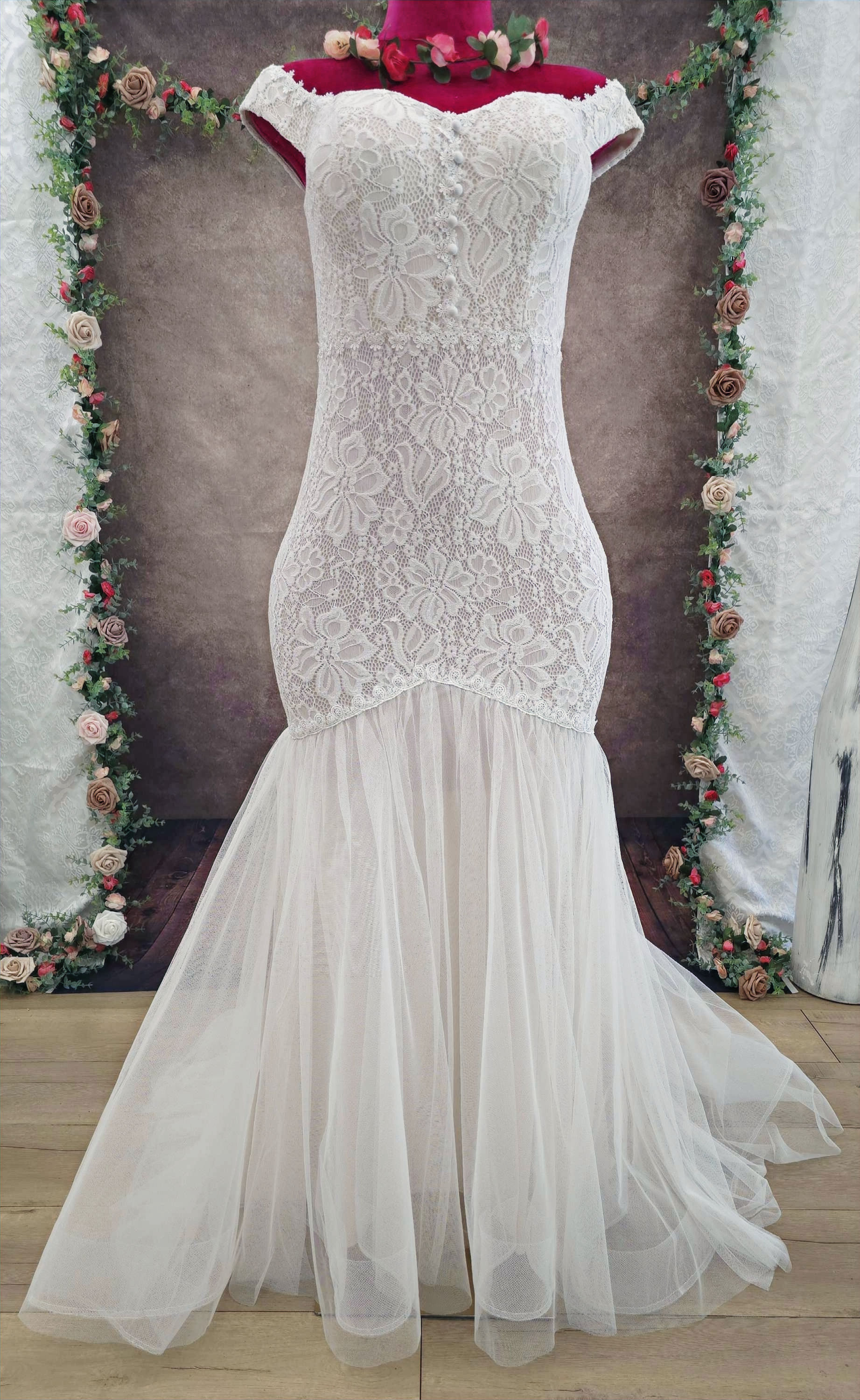 Vista del cuerpo entero del vestido, que combina un cuerpo de encaje floral ajustado con una falda de tul ligero estilo sirena. Este diseño abraza las cuervas con suavidad y deja una impresión delicada y femenina.