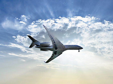 Jet flying against a cloudy sky with sunbeams breaking through. The airplane is white, reflecting the light, creating a dynamic scene.