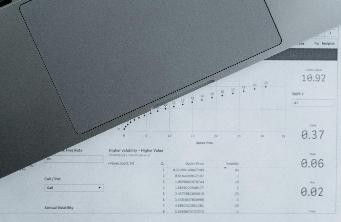 Laptop on document showing financial data with charts and numbers in grayscale, featuring values like 19.97, 0.37, and 0.02.