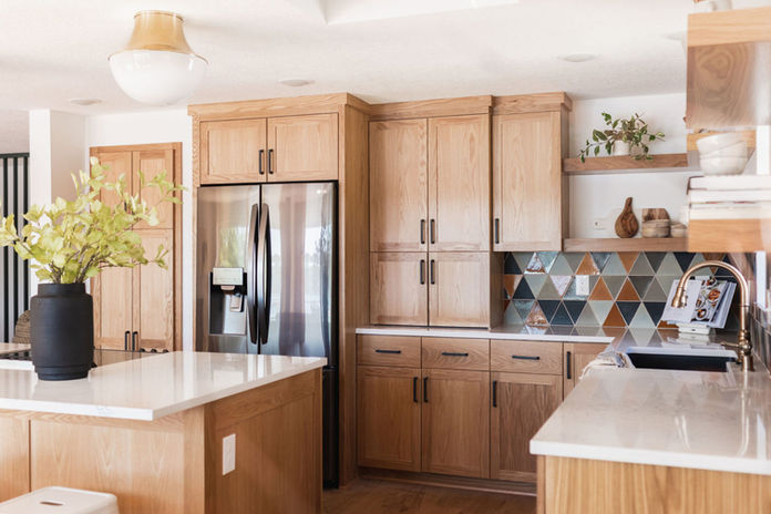 Light brown cabinets, black hardware, accent tile backsplash