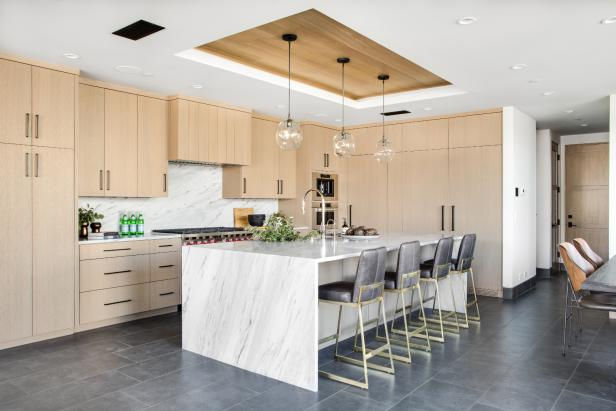 Brown cabinets, white quartz waterfall island, quartz backsplash