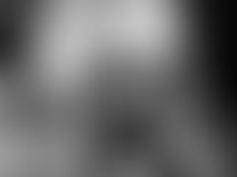Person taking photo of two people with a smartphone in a studio setting. Black and white image with blurred background and bright lighting.