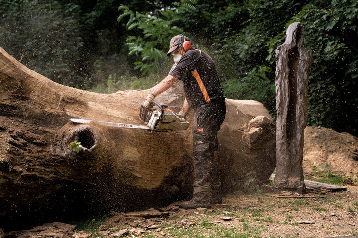 Authentisches Künstler-Portrait von Stephan Guber: Ein ruhiger Moment vor seinen Holzskulpturen bei natürlichem Licht.