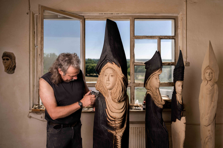 Authentisches Künstler-Portrait von Stephan Guber: Ein ruhiger Moment vor seinen Holzskulpturen bei natürlichem Licht.