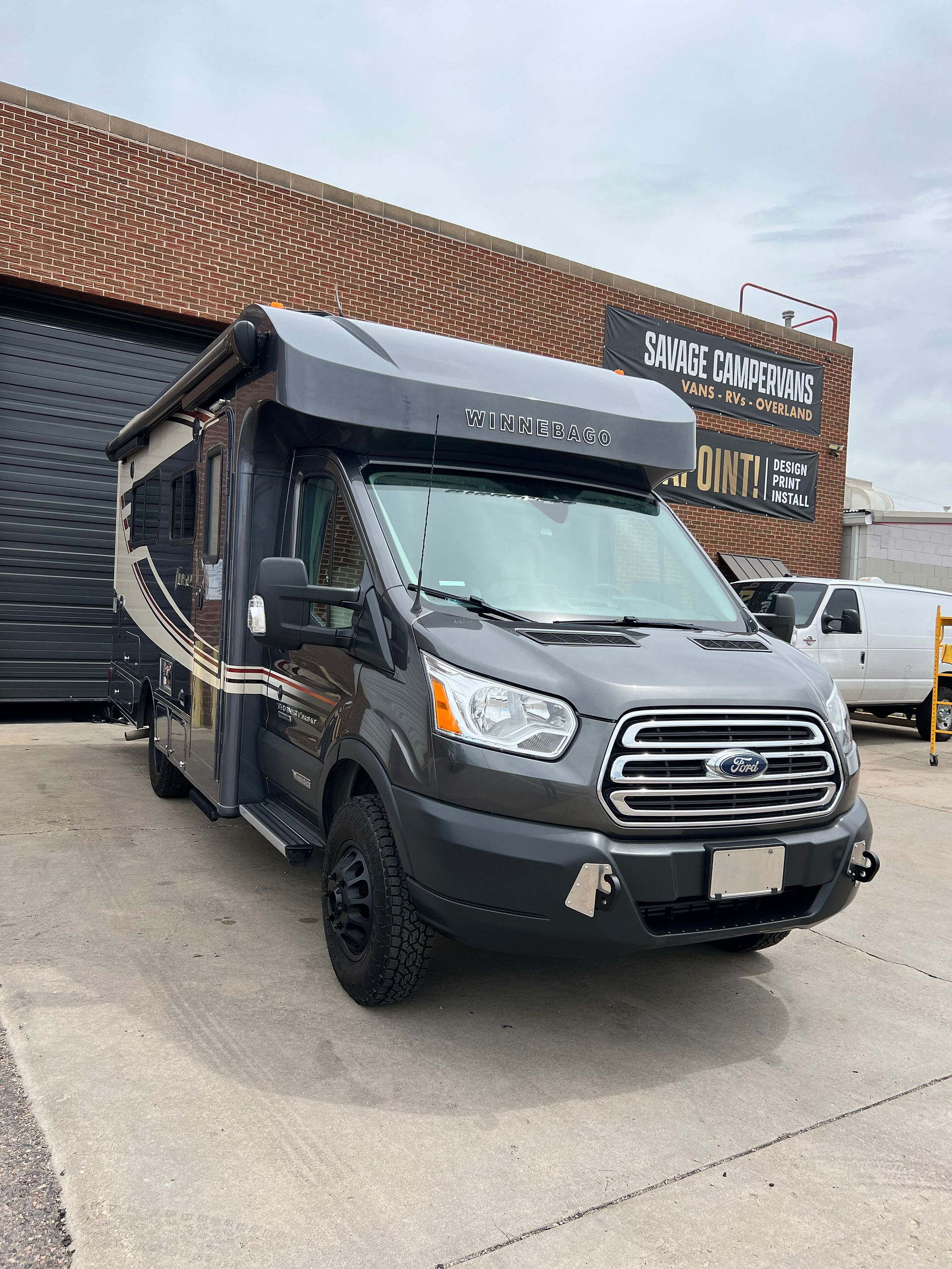 Winnebago Fuse with 2-inch WeldTec lift kit and Method wheels parked outside Savage Campervan & RV shop in Denver.