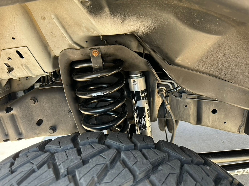 Close up of WeldTec Designs lift kit suspension with Fox shocks on Ford Econoline