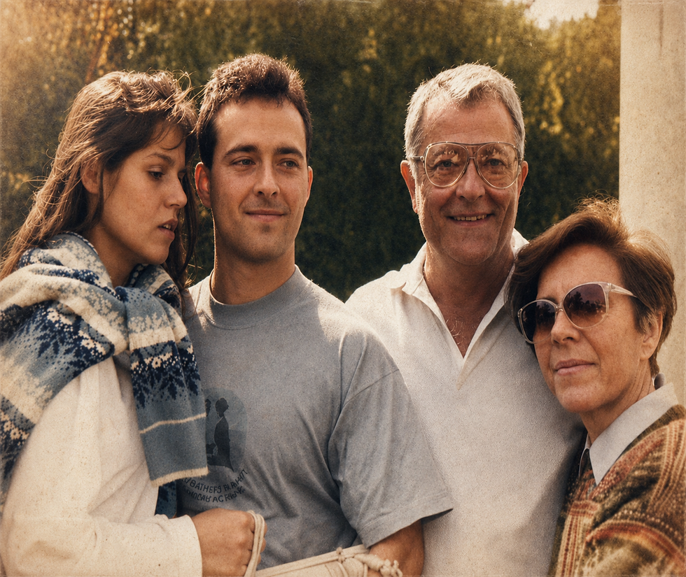 Uma fotografia de estilo analógico com estética dos anos 1990 retratando quatro pessoas em um momento de alívio e união familiar. À esquerda, uma jovem de cabelos longos usa um cachecol estampado azul e branco sobre os ombros e apoia-se carinhosamente em um jovem de camiseta cinza-azulada, que esboça um leve sorriso de tranquilidade. Ao lado deles, um homem mais velho de óculos de grau e camisa polo branca sorri calorosamente para a câmera. À direita, uma mulher mais velha de óculos de sol escuros e cabelos curtos encosta a cabeça suavemente em seu ombro. O fundo apresenta folhagens verdes desfocadas e uma luz suave de fim de tarde, criando um ambiente acolhedor e nostálgico, com grão característico de foto revelada antiga.