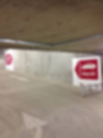 Exit sign painted on a wall with a red box and arrow surrounding it and a car icon directing the cars through the car park.