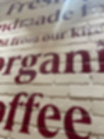 Purple Lettering on a white brick wall.