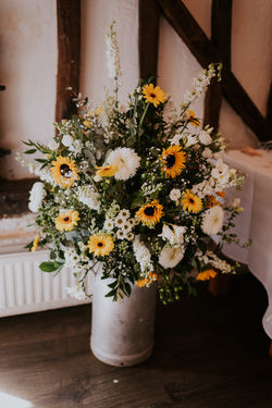 A large milk churn is filled with sunflowers and white flowers for a wedding at Cantley House Hotel