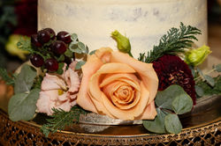 Close up of a peach rose and burgundy hypericum berries on a wedding cake at Cliveden House