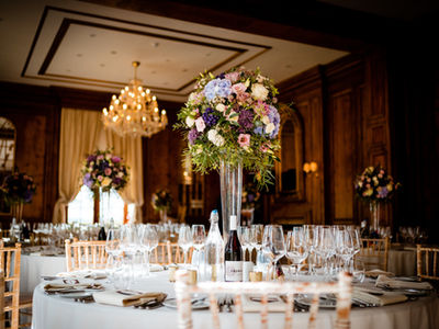 Tall lilac and purple wedding centrepieces filled with hydrangea, roses, allium, eustoma and eucalyptus at Hedsor House.