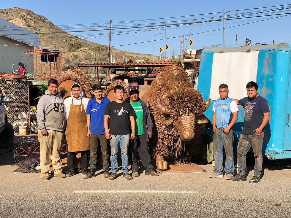 Artisans beside large metal buffalo sculptures in a Popotla workshop