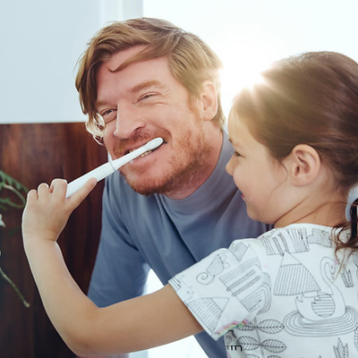 Chica cepillando los dientes de papá