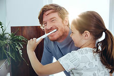 Chica cepillando los dientes de papá