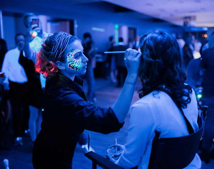 HappyCake Face Painter painting face of a woman with glow in the dark face paint at an adults event in the Bay Area