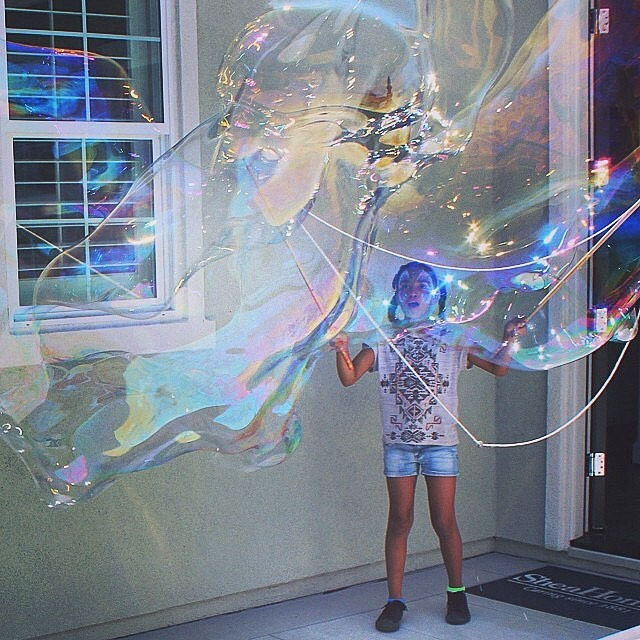 Girl outside of house creating giant bubbles for children and adult events in the Bay Area