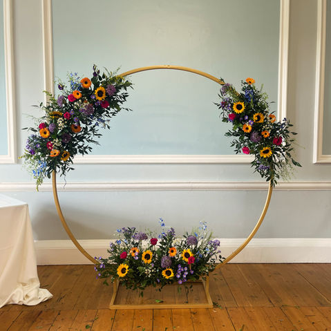 Moorgate arch with 3 floral arrangements attached in bright colours