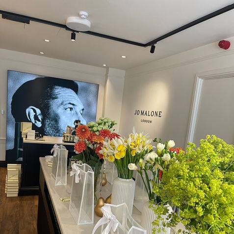 Vases of flowers on white counter top in retail shop Jo Malone